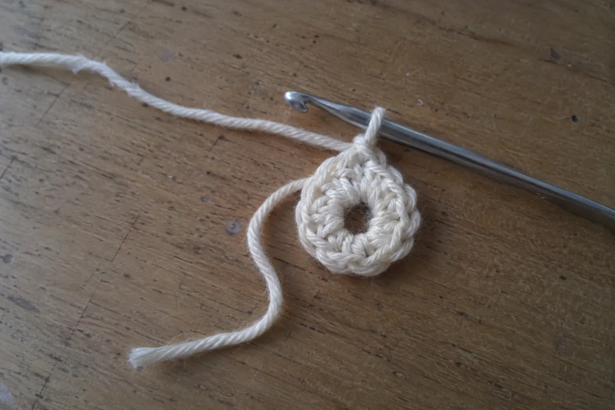 Début d’un ouvrage circulaire au crochet avec un fil libre visible.